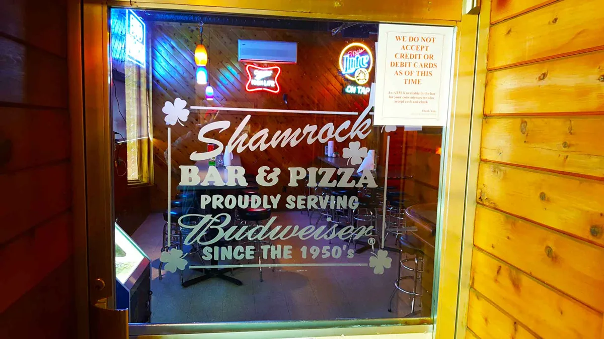 The Shamrock entrance door with its painted bar and pizza sign