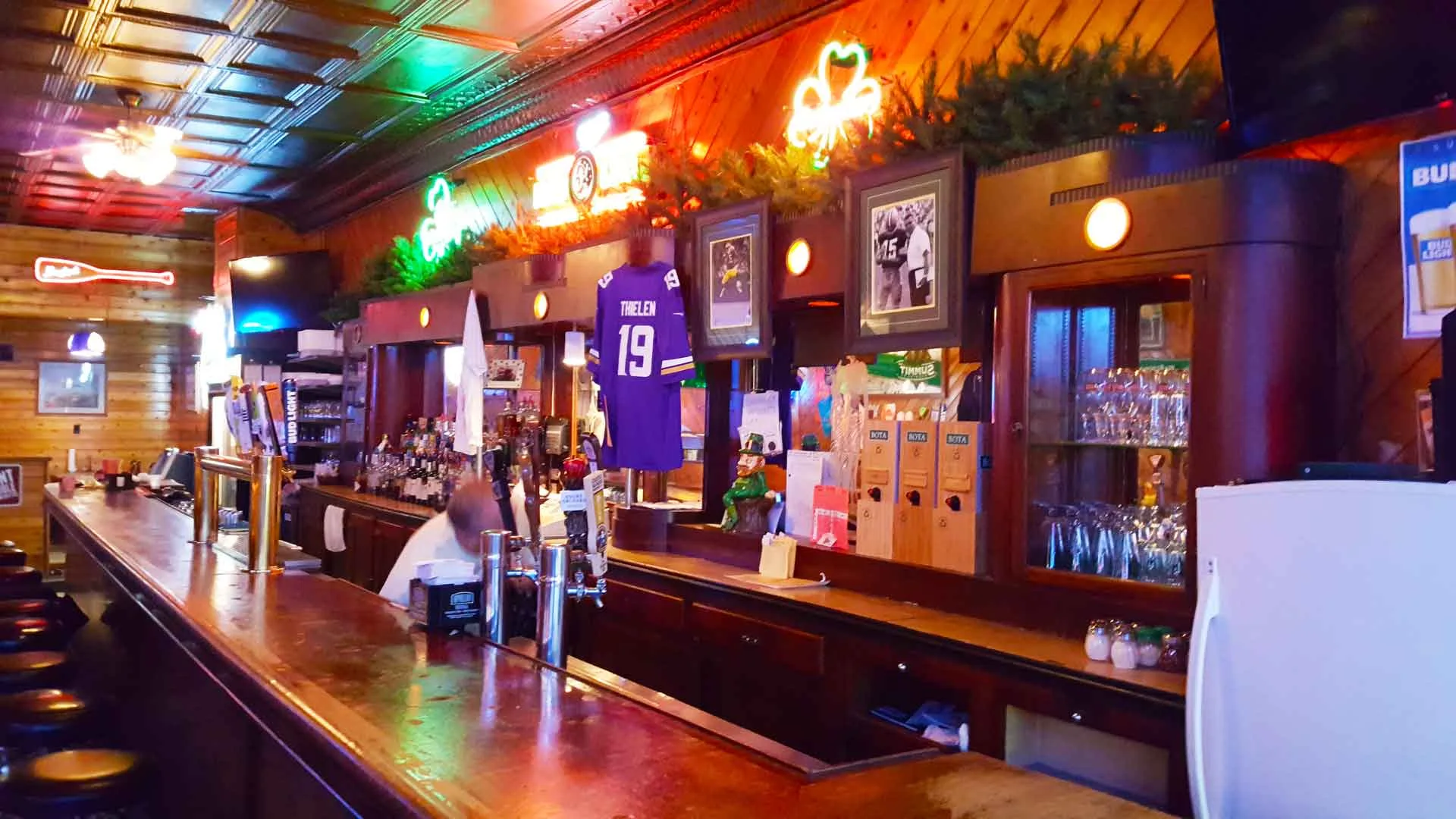 The long wood bar at Shamrock, with brass taps, wood paneling and warm lights